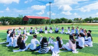 people sitting on green lawn grass while doing hands up at daytime